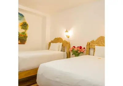 two beds in a room with white walls and flowers at Inkarri Regocijo Plaza in Cusco