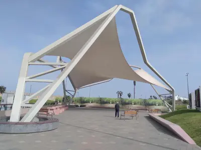 a man is standing under a large white sculpture at Like/Home in Lima