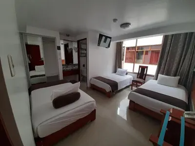 a hotel room with two beds and a mirror at Flower's House MachuPicchu in Machu Picchu