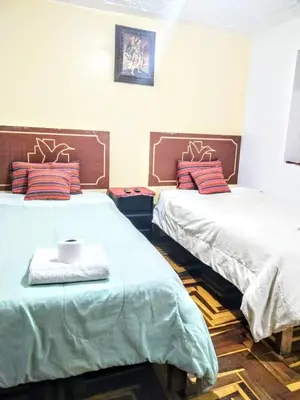 a room with two beds and a table in it at Hospedaje Apu Salka in Cusco