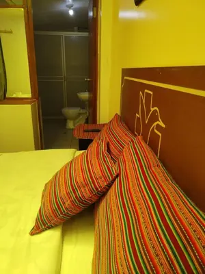 a bed with a colorful striped pillow on it at Hospedaje Apu Salka in Cusco