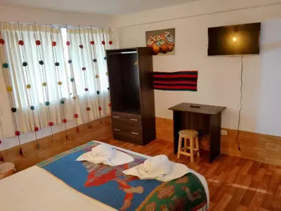 a room with a bed and a desk and a television at Inca Town In in Cusco