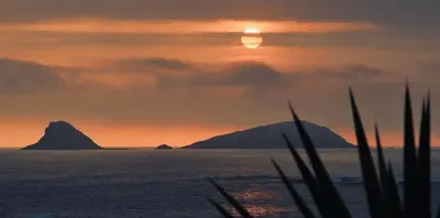 a sunset over the ocean with a mountain in the background at Almar Punta Hermosa in Punta Hermosa