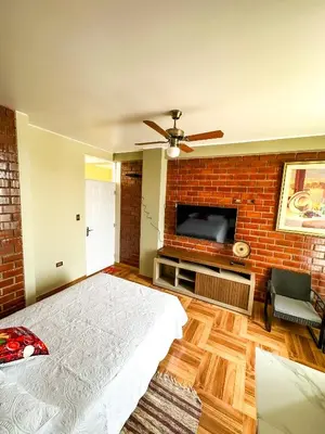a bedroom with a brick wall and a bed and a tv at Viñedo Sotelo - Hospedaje y Glamping in San Juan Bautista