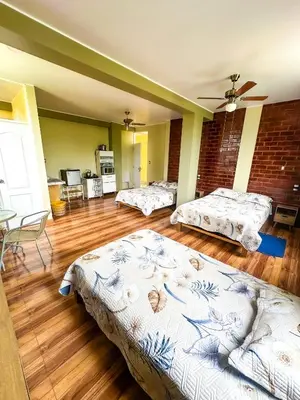 a room with three beds and a brick wall at Viñedo Sotelo - Hospedaje y Glamping in San Juan Bautista