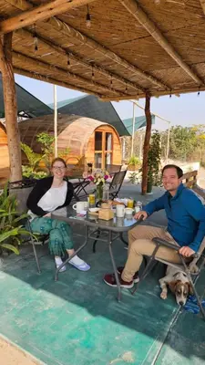 a man and a woman sitting at a table with a dog at Viñedo Sotelo - Hospedaje y Glamping in San Juan Bautista