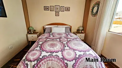 a bedroom with a bed with a pink and white blanket at Puma Wasi, céntrico, acogedor, bien iluminado in Cusco