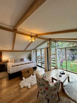 a bedroom with a bed and a couch and a chair at Spirit Of The River Lodge in Cusco
