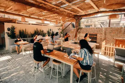 a group of people sitting at a table with laptops at Viajero Huacachina Hostel in Ica