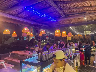 a group of people sitting at a bar in a restaurant at Viajero Huacachina Hostel in Ica