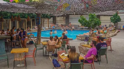 a group of people sitting around a swimming pool at Viajero Huacachina Hostel in Ica