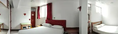 a small room with two beds and a mirror at Hostal Reyna in Lima