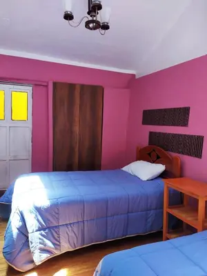 a bedroom with a bed and a pink wall at Yllari's Inn in Cusco