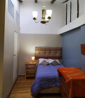 a bedroom with a blue bed and a chandelier at Yllari's Inn in Cusco