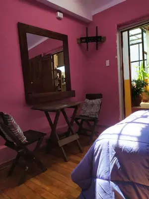 a bedroom with a mirror and a table and chairs at Yllari's Inn in Cusco