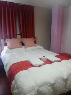 a large bed with two towels and a cup on it at Yllari's Inn in Cusco