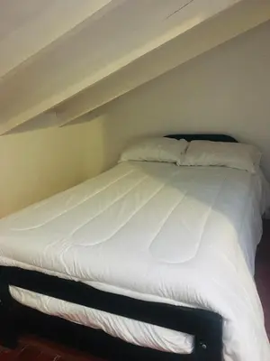 a bed with white sheets and pillows in a room at Washichay in Cusco