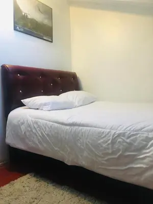 a bed with white sheets and a brown headboard at Washichay in Cusco