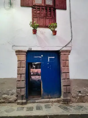 a blue door on a building with two potted plants at Washichay in Cusco