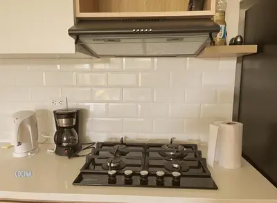 a kitchen counter with a stove top with a coffee maker at 2BR Apartamento Moxie Paracas con Terraza y AC en 1r Piso in Paracas