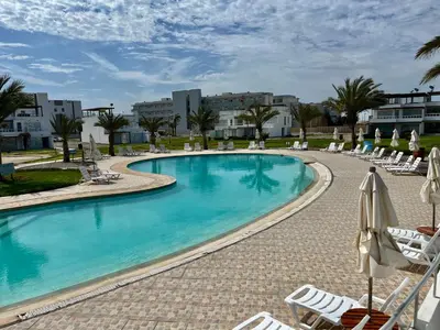 a large swimming pool with lounge chairs and umbrellas at 1er Piso Vista a Bahía Paracas - Las Velas 102 T1 in Paracas