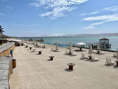 a beach with chairs and umbrellas and the ocean at 1er Piso Vista a Bahía Paracas - Las Velas 102 T1 in Paracas