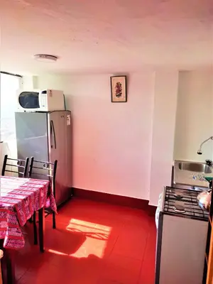 a kitchen with a refrigerator and a table with a red floor at APARTAMENTO VISTA IMPERIAL II Mirador Panoramico in Cusco