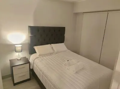 a bedroom with a bed with white sheets and a lamp at Audacity Moderno Departamento in Lima