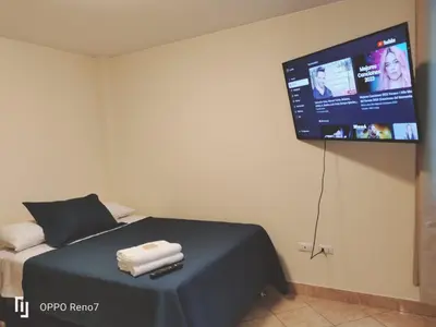 a bedroom with a bed with a tv on the wall at Warmisitay HOME individual in Lima