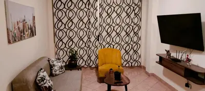 a living room with a yellow chair and a flat screen tv at Warmisitay HOME individual in Lima