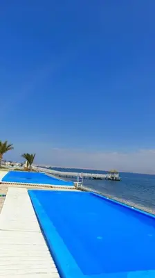 a row of blue swimming pools next to the ocean at Condominio Nautico Paracas in Pisco