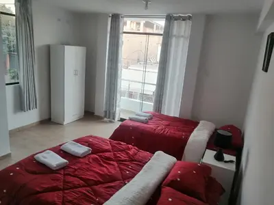 a bedroom with two beds with red sheets and a window at Alemar's House in Nazca
