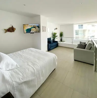 a white bedroom with a white bed and a couch at Departamento de Playa San Bartolo SOL ARENA & MAR in San Bartolo