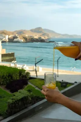 a person holding a glass with an orange drink at Departamento de Playa San Bartolo SOL ARENA & MAR in San Bartolo