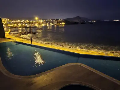 a swimming pool with a view of the water at night at Departamento de Playa San Bartolo SOL ARENA & MAR in San Bartolo