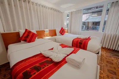 two beds in a hotel room with red and white blankets at DANNA INN in Machu Picchu