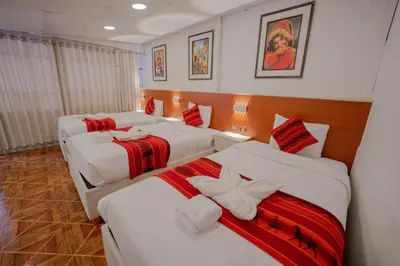 a hotel room with three beds with red and white blankets at DANNA INN in Machu Picchu