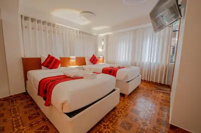 two beds in a hotel room with red accents at DANNA INN in Machu Picchu
