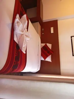 a bed with a red and white blanket and pillows at DANNA INN in Machu Picchu