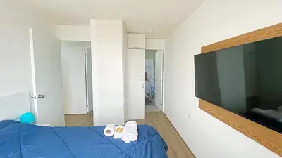 a bedroom with a blue bed and a flat screen tv at Depa playa San Bartolo 3 camas piscina wifi juegos in Lima