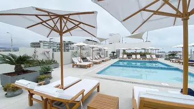 a pool with chairs and umbrellas on a hotel at Depa playa San Bartolo 3 camas piscina wifi juegos in Lima