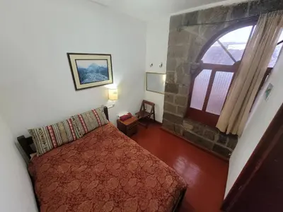a bedroom with a bed and a stone fireplace at Hostal CASA CUSCO in Cusco