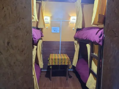 a small room with two bunk beds with a table at Hostal CASA CUSCO in Cusco