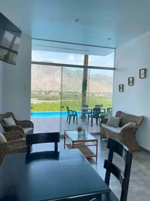 a living room with chairs and tables and a large glass window at Mirador del Paraiso in Lunahuaná