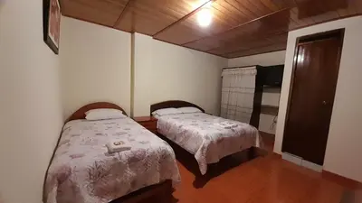 a bedroom with two beds and a tv in it at HOSPEDAJE D`NOA En el centro de Oxapampa in Oxapampa