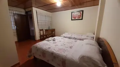 a bedroom with two beds and a table at HOSPEDAJE D`NOA En el centro de Oxapampa in Oxapampa