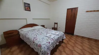 a bedroom with a bed with a floral bedspread at HOSPEDAJE D`NOA En el centro de Oxapampa in Oxapampa