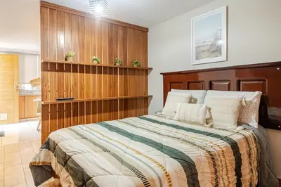 a bedroom with a large bed with a wooden headboard at Acogedor Loft equipado con Sofá cama en Matellini in Lima