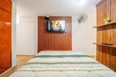 a bedroom with a bed with a tv on the wall at Acogedor Loft equipado con Sofá cama en Matellini in Lima