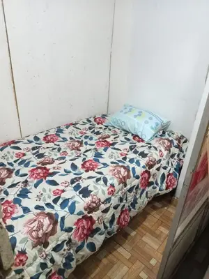 a bed with a floral comforter and a pillow at POSADA CHABELITA in Lima
